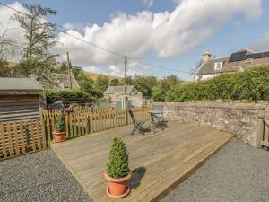 a wooden deck with two potted plants and a table at Kirk Cottage in Hownam