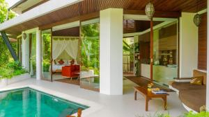 an outdoor living room with a swimming pool and a house at Cahaya Indah Villas in Ubud