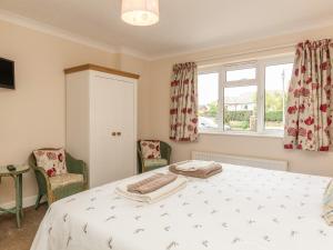 a bedroom with a bed and two chairs and a window at Pipistrelle Lodge in Plymtree