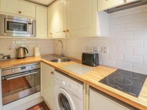 a kitchen with a sink and a stove top oven at Kirk Cottage in Hownam
