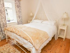 a white bed with a white canopy in a bedroom at Sandy Cottage in Linton