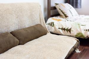 un sofá con una almohada en el suelo de madera en Luxes Hiroshima2030 ラクセス ヒロシマ2030, en Hiroshima