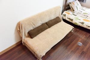 un sofá con una manta junto a una cama en Luxes Hiroshima2030 ラクセス ヒロシマ2030, en Hiroshima