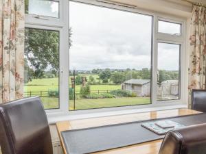 a dining room with a table and two windows at Pipistrelle Lodge in Plymtree
