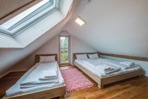 two beds in a attic room with a window at Ferienhaus Tor zum Allgäu in Vogt