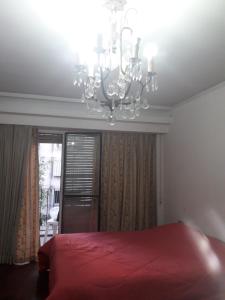 a bedroom with a red bed and a chandelier at Hombres Negociadores, Artistas Huéspedes Especiales in Rosario