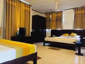 una camera d'albergo con due letti e una televisione di Lavendish Okrin Hotel a Kataragama