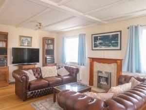 ein Wohnzimmer mit Ledermöbeln und Kamin in der Unterkunft 11 Pendarves in Saint Merryn
