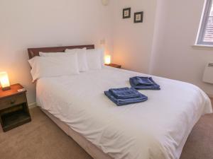 een slaapkamer met een wit bed en 2 handdoeken bij The Moorings in Isle of Whithorn