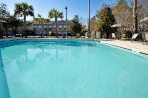 a large blue swimming pool with chairs and trees at Moncks Corner Inn in Moncks Corner