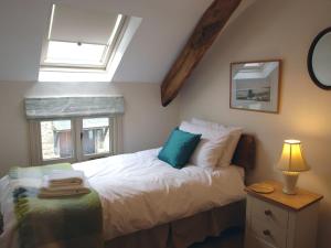 a bedroom with a bed with a blue pillow and a window at The Linhay in Throwleigh
