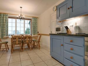 a kitchen with blue cabinets and a table with a dining room at Higher Tumrose in Blisland