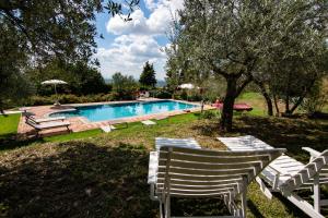 einen Pool mit Stühlen und einem Sonnenschirm in der Unterkunft Casale Il Trecento in Castiglion Fiorentino