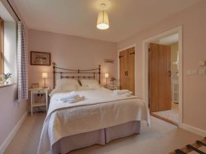 1 dormitorio con 1 cama grande con sábanas blancas en 2 Shippen Cottages en Cotleigh
