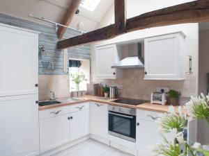 a kitchen with white cabinets and wooden beams at Saltwind Granary in Hartland