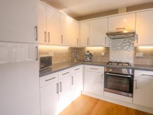 a kitchen with white cabinets and stainless steel appliances at 11 Pendarves in St Merryn