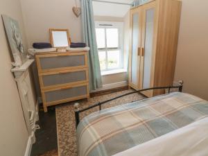 a bedroom with a bed and a dresser and a window at Glasfryn in Holyhead