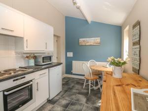a kitchen with a table and a blue wall at Glasfryn in Holyhead