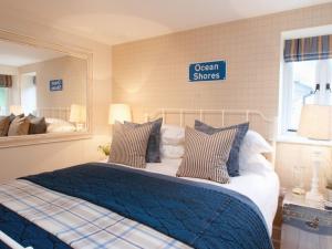 a bedroom with a bed with a blue comforter and a mirror at Saltwind Granary in Hartland