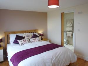 a bedroom with a large white bed with purple pillows at The Hayloft in Breage