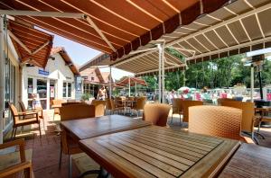 an outdoor patio with wooden tables and chairs at Camping Officiel Siblu Les Pierres Couchees in Saint-Brevin-les-Pins