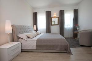 a white bedroom with a large bed and windows at B&B Ai Filari in Baone