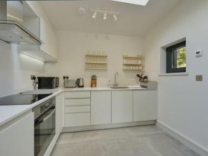 a white kitchen with white cabinets and a sink at Gardeners Cottage in Talaton