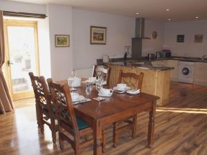 a kitchen with a wooden table with chairs and a kitchen with a counter at Butterdon Barn in Moretonhampstead