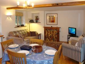 uma sala de estar com uma mesa com cadeiras e um sofá em The Linhay em Throwleigh