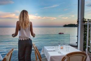 Una mujer parada en una mesa mirando hacia el océano en Il Cefalo Hotel & Restaurant, en Castellabate