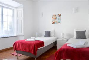 オエイラスにあるOeiras 3 - Checkinhomeの白いベッドルーム(赤いシーツを使用したベッド2台付)