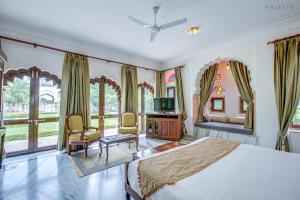 a bedroom with a bed and a tv and some windows at Talabgaon Castle Heritage Resort in Sarīma