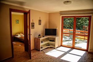 a living room with a television and a door to a balcony at Domki Beskid in Rzyki