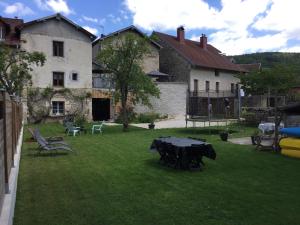 einen Garten mit einem Tisch und Stühlen sowie einem Gebäude in der Unterkunft Gîte sur Loue in Ornans