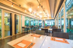a dining room with tables and chairs and windows at Citrus Sukhumvit 11 by Compass Hospitality in Bangkok