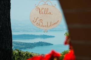 a sign hanging from a tree with a view of a lake at San Bartolomeo Suite in Castel Rigone