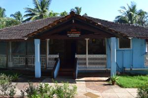ein blaues Gebäude mit einer Veranda mit einem Schild darauf in der Unterkunft O Camarao in Calangute