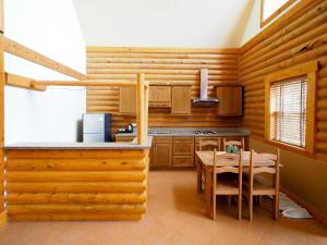 Toscana Log Home في Ban Nong Rua: مطبخ بجدران خشبية وطاولة وكراسي