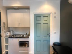 eine Küche mit einer blauen Tür und einem Waschbecken in der Unterkunft Stylish Studio Room in Brixton - E in London