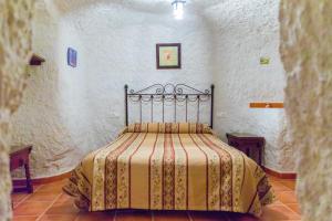 Un dormitorio con una cama en una habitación blanca. en Casas Cueva Molino Fuencaliente, en Huéscar