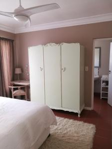 a bedroom with a bed and a white cabinet at Lucias Cottage in Cape Town