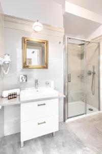 a white bathroom with a sink and a shower at Apartamenty Pod Baranem in Krakow