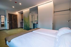 Un dormitorio con una gran cama blanca y una pared de cristal en Hotel y Estudios DCeres Estancias en Santa María de Mave