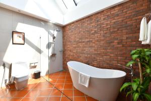 a bathroom with a white tub and a brick wall at El Barrio Lanna in Chiang Mai