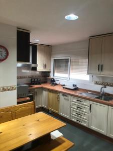 a kitchen with white cabinets and a wooden table at El Balcón de Sevilla in Seville