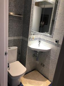 a bathroom with a toilet and a sink and a mirror at El Balcón de Sevilla in Seville