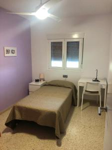 a bedroom with a bed and a table and a window at El Balcón de Sevilla in Seville