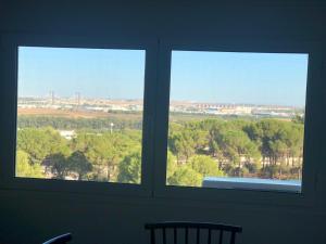 two windows in a room with a view of trees at El Balcón de Sevilla in Seville