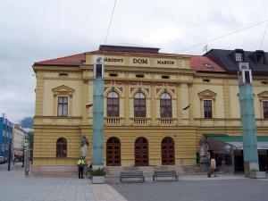 a large yellow building with people standing in front of it at Moderný Byt Pri Pešej Zóne in Martin