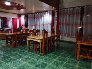 un comedor con mesas de madera, sillas y cortinas en Trekkers Lodge and Cafe, en Banaue
